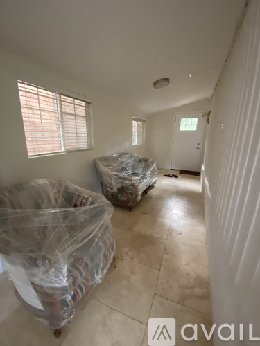 A room with two plastic wrapped couches and a tiled floor.