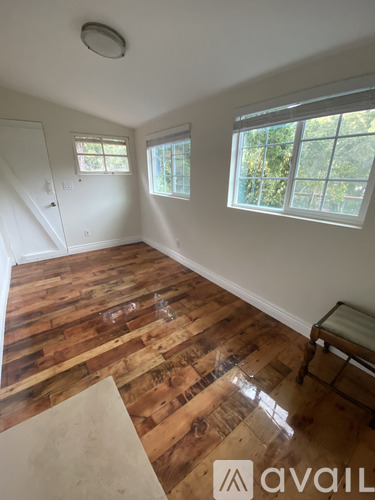 A room with wooden floors and a window overlooking trees.