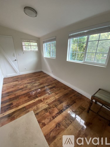 A room with wooden floors and a window overlooking trees.