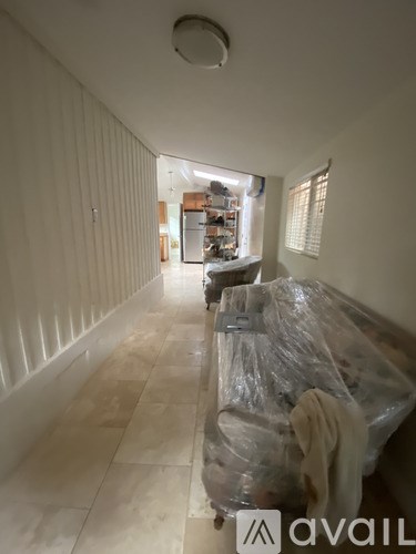 A long hallway with a plastic wrapped object on the floor.