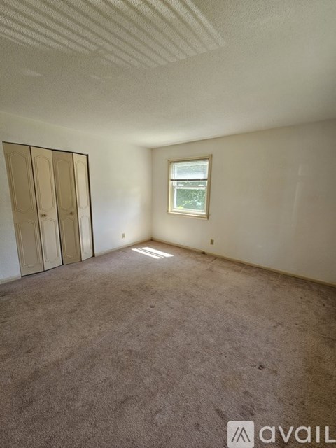 A room with a carpeted floor, a window, and a door.