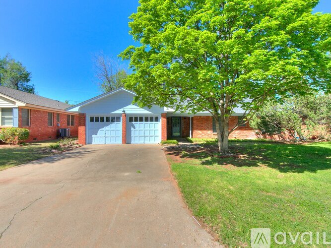 A house with a driveway and a tree in front.