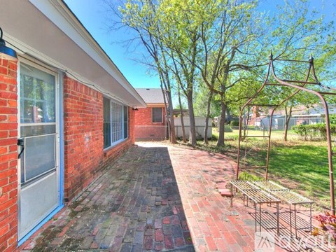 A red brick house with a white door and a bench in front of it.