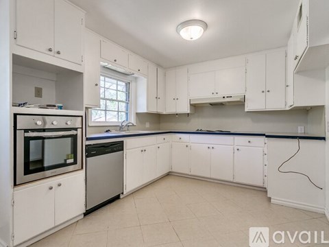A kitchen with white cabinets and a window.