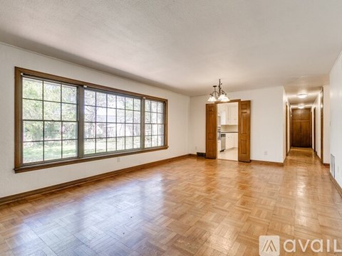 A spacious room with wooden floors and a large window.