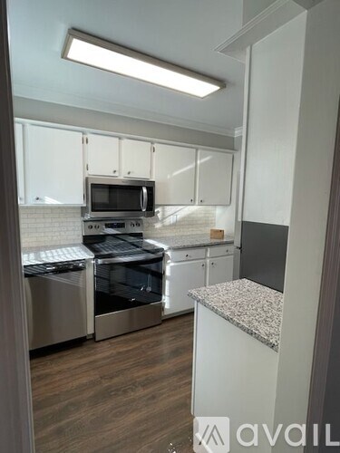 A kitchen with white cabinets and a granite counter.