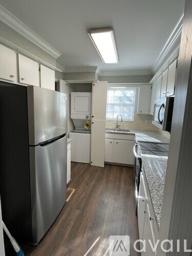 A kitchen with a black refrigerator and white cabinets.