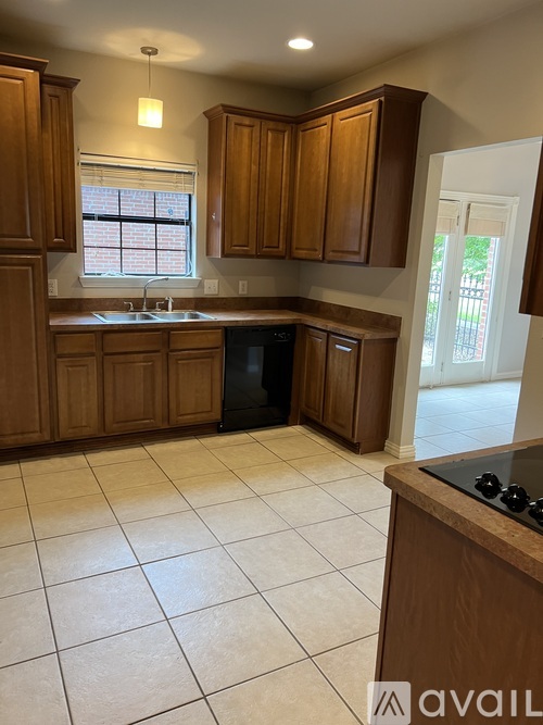 A kitchen with wooden cabinets and a black dishwasher.