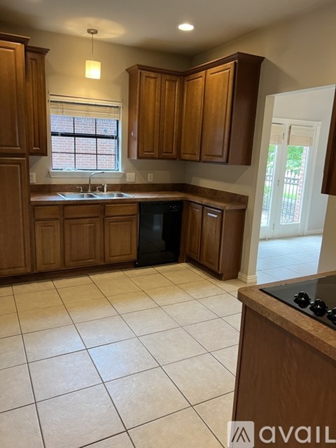 A kitchen with wooden cabinets and a black dishwasher.
