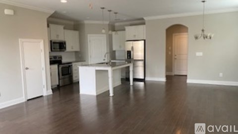 A kitchen with white cabinets and a wooden floor.