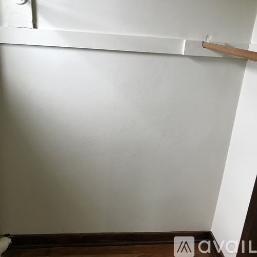 A white wall with a wooden handle on it.