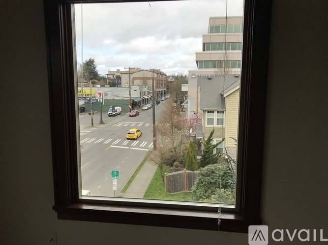 A view from a window looking out at a street with cars and buildings.