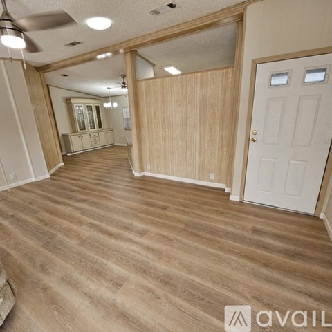 A spacious room with wooden flooring and a white door.