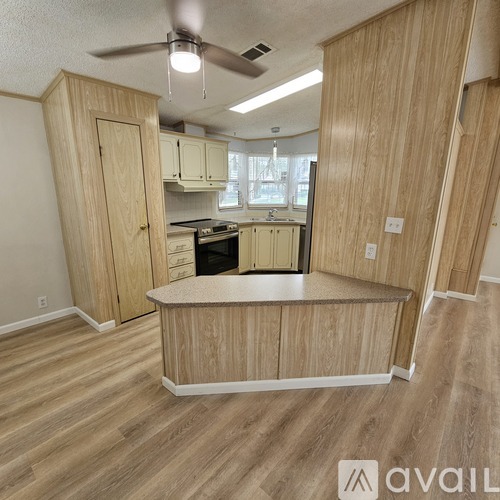 A kitchen with wooden cabinets and a fan on the ceiling.