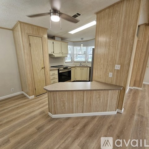 A kitchen with wooden cabinets and a fan on the ceiling.