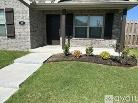 A house with a black door and windows with a small garden in front.