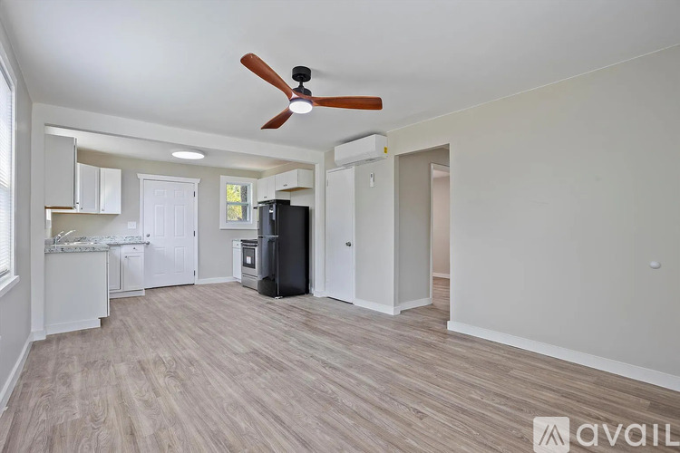 A spacious living room with a ceiling fan and lighting fixtures.