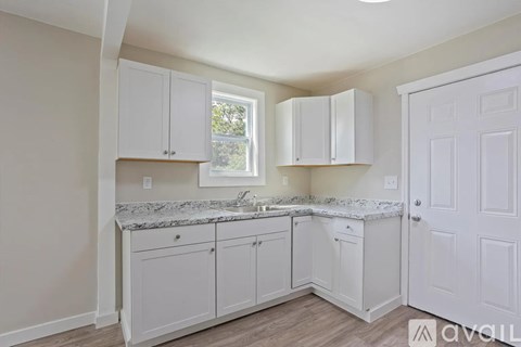 A kitchen with white cabinets and a marble countertop.