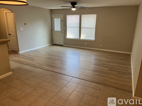 A spacious room with a fan and tile flooring.
