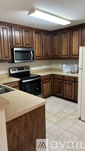 A kitchen with wooden cabinets and a black microwave.