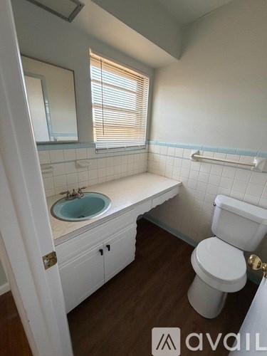 A bathroom with a toilet, sink, and mirror.