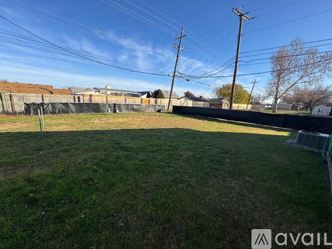 A grassy field with a fence and utility poles in the background.