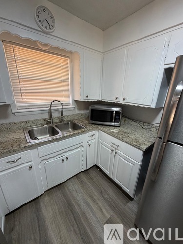 A kitchen with white cabinets and a granite countertop.