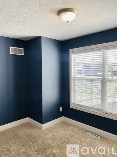 A room with blue walls and a window with blinds.