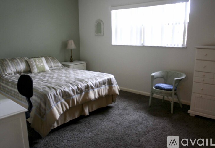 A bedroom with a bed, chair, and window.
