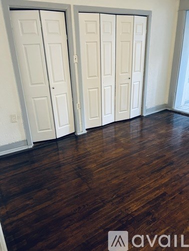 A room with two white doors and a wooden floor.