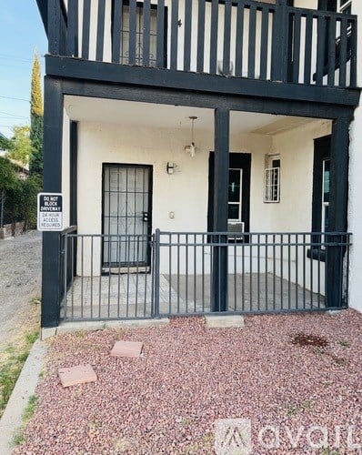A black and white house with a gate and a sign in front.