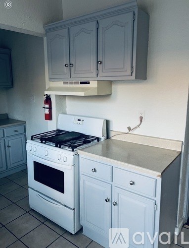 A white stove in a kitchen with grey cabinets.