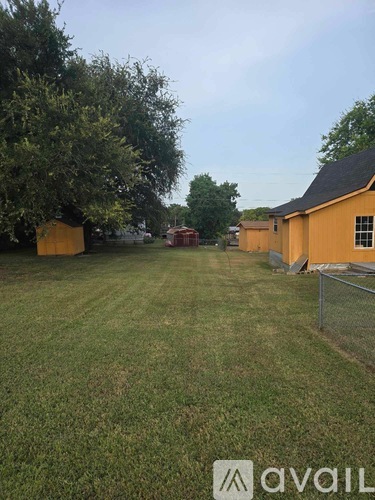A grassy field with a fence and a building in the background.