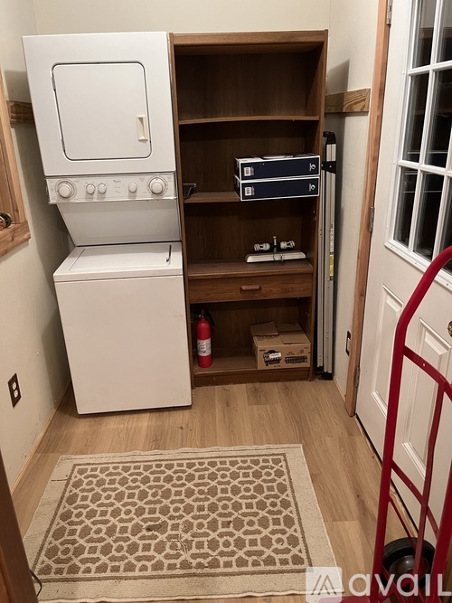 A small kitchen with a white oven and a wooden shelf.