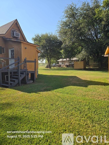 A wooden house with a porch and a tree in the background.