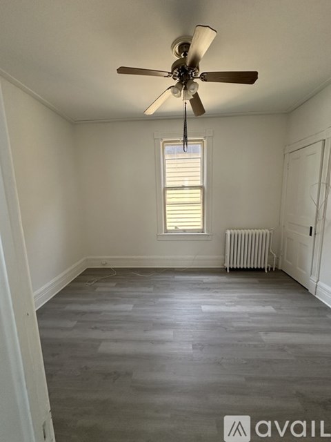 A room with a ceiling fan and a window with blinds.