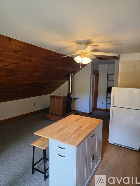 A kitchen with a wooden island and a white refrigerator.
