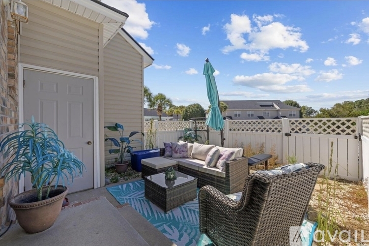 A patio with a wicker chair and table with a blue umbrella.