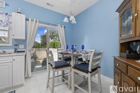 A dining area with a table set for two and a kitchen area with a sink and stove.