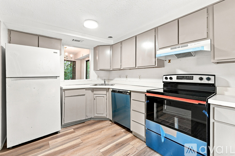 A kitchen with white appliances and wooden floors.