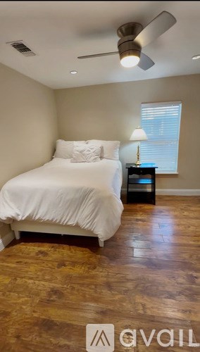 A bedroom with a bed, nightstand, and a window with blinds.