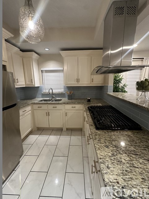 A kitchen with white cabinets and a granite countertop.
