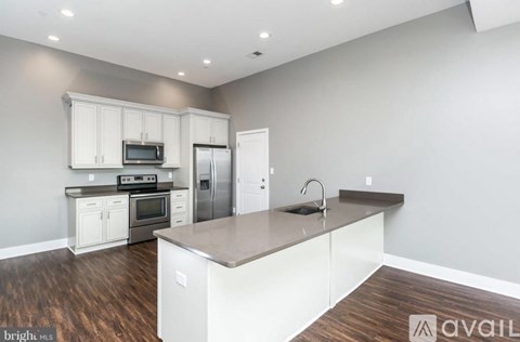 A kitchen with white cabinets and a wooden floor.