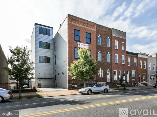 A street view of a multi-story building with a car parked in front.