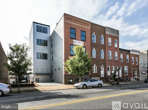 A street view of a multi-story building with a car parked in front.