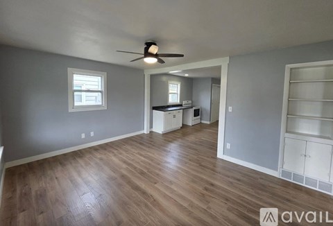 A room with a ceiling fan and wooden flooring.