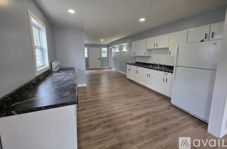 A kitchen with white cabinets and a black countertop.
