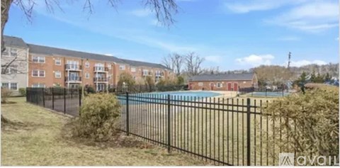 A black fence surrounds a pool in a sunny backyard.