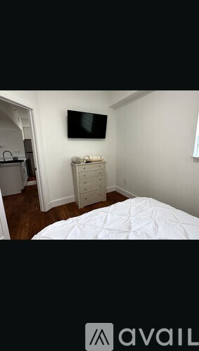 A bedroom with a bed, dresser, and a television.