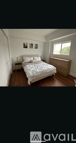 A bedroom with a bed, nightstands, and pictures on the wall.
